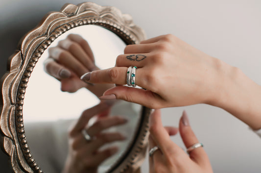 Close-up of hands with rings in front of a decorative mirror