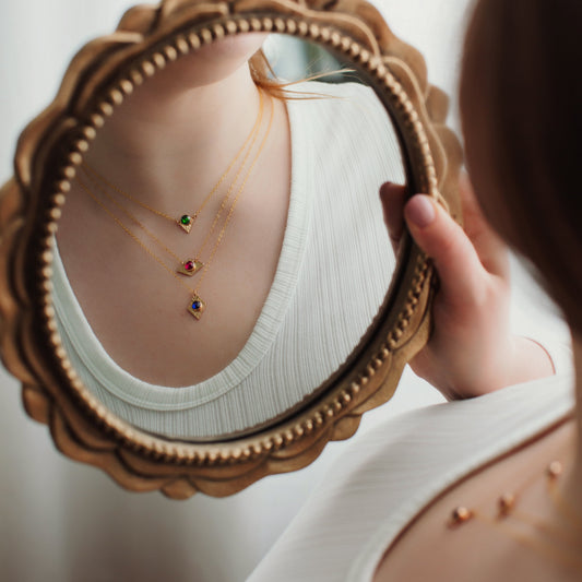 Person holding a decorative mirror with a reflection of jewelry.