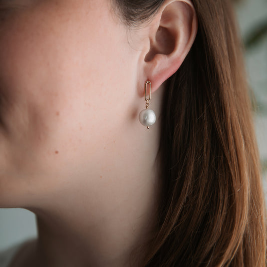 Close-up of a person wearing a pearl earring with a blurred background