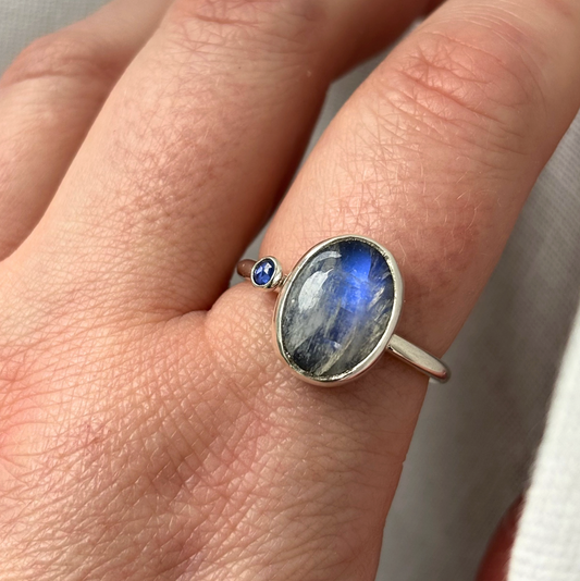 silver ring with a blue gemstone on a finger