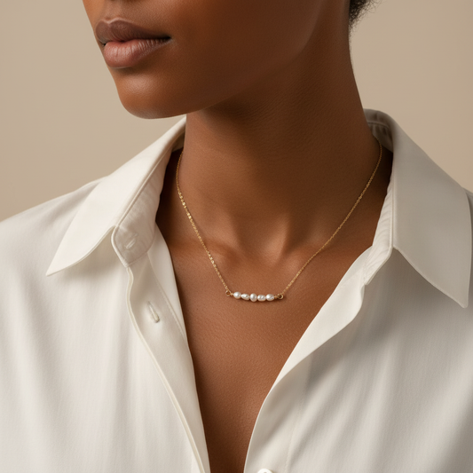 Woman wearing a gold necklace with pearls against a neutral background