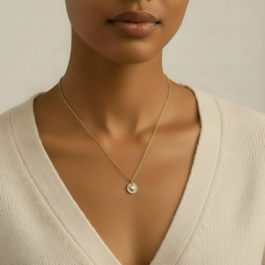Woman wearing a gold necklace with a small pendant against a neutral background