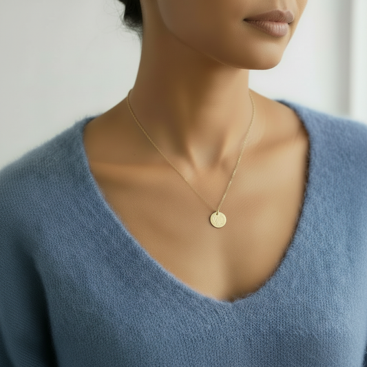 Person wearing a gold necklace with a blue sweater