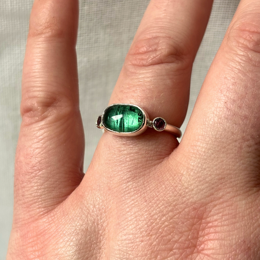 Silver ring with a green gemstone on a finger