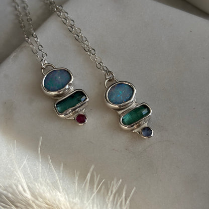 Silver necklace with gemstone pendants on a textured surface