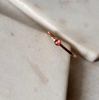 Gold ring with a red gemstone on a marble surface