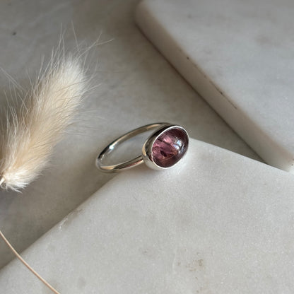 Silver ring with a purple gemstone on a neutral background