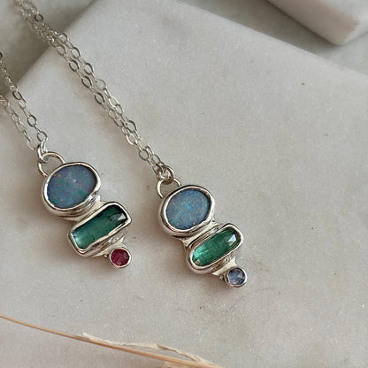 Two silver necklaces with Australian opal pendants on a light background
