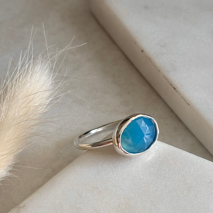 Silver ring with a blue chalcedony stone on a light background