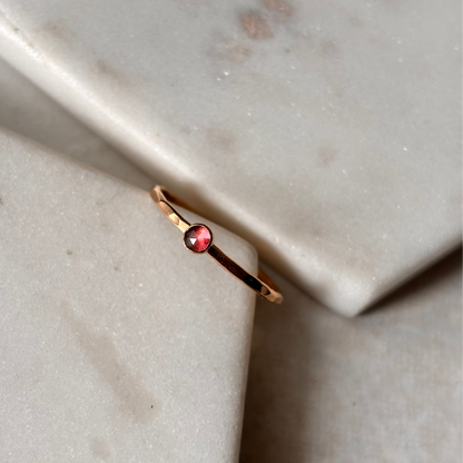 Gold ring with a pink tourmaline gemstone on a marble surface