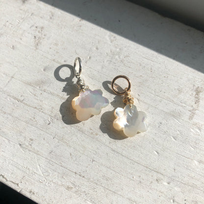 Two Mother of Pearl cloud charms, one with a silver hoop and the other with a gold-filled hoop in natural sunlight.