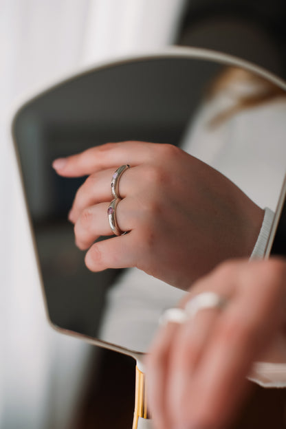Close-up of a hand with a ring holding a mirror