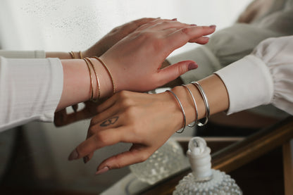 Close-up of two people's hands with bracelets on a blurred background