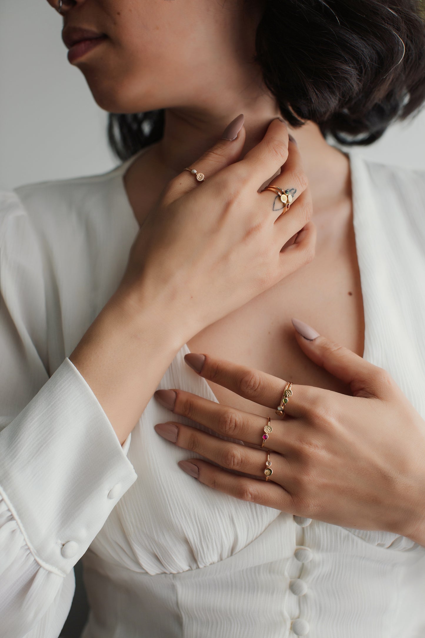 Close-up of a person wearing multiple gold rings on a white shirt.