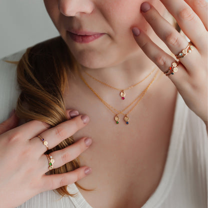 Woman wearing gold necklaces and rings, with a neutral background