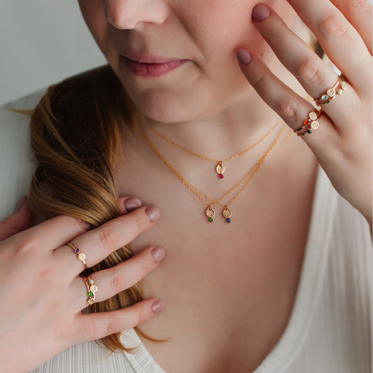 Woman wearing gold necklaces and rings, with a neutral background
