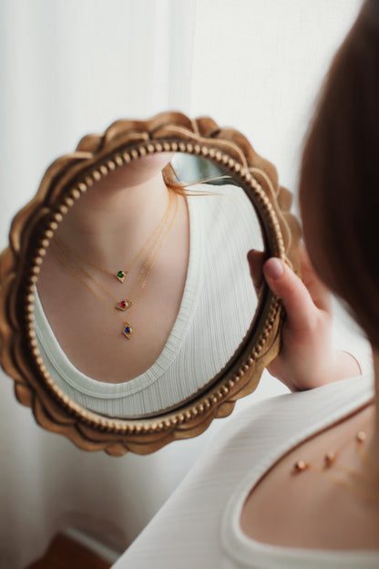Person holding a decorative mirror with a reflection of jewelry.