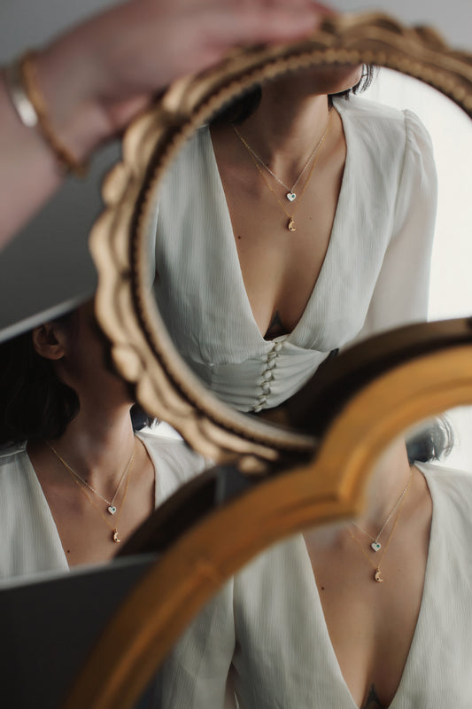 Person wearing a necklace with a mirror reflecting their reflection.