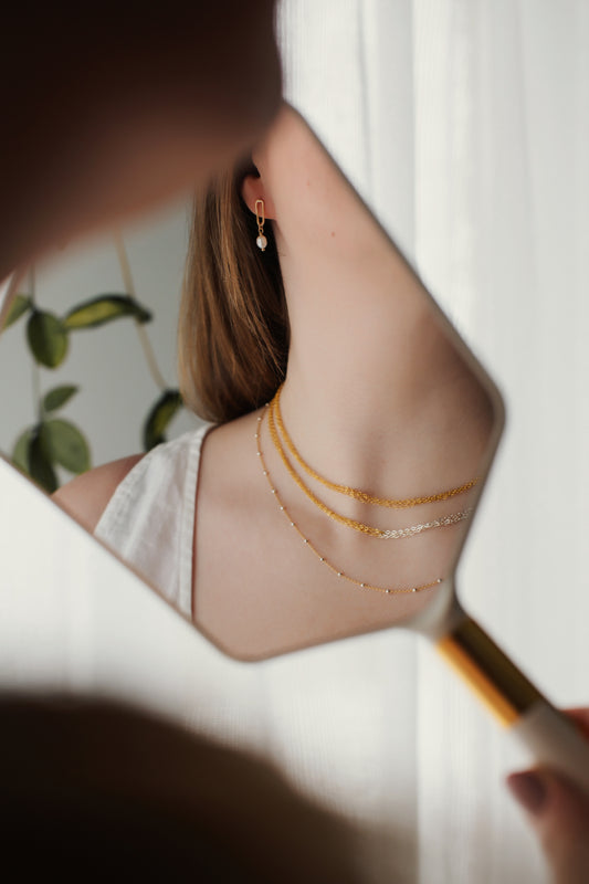 Person wearing gold necklaces with a blurred background