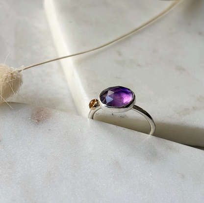Silver ring with a purple gemstone on a light background