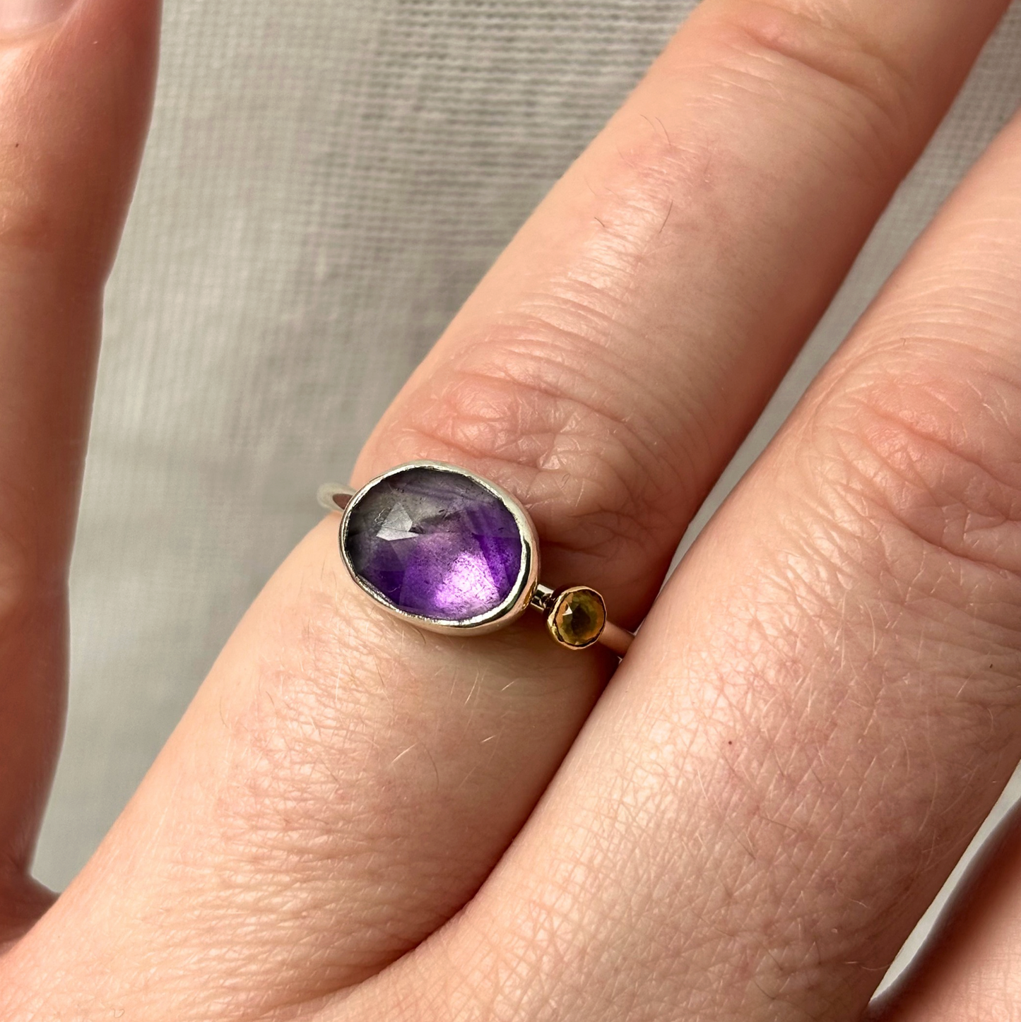 Amethyst ring on a finger with a neutral background