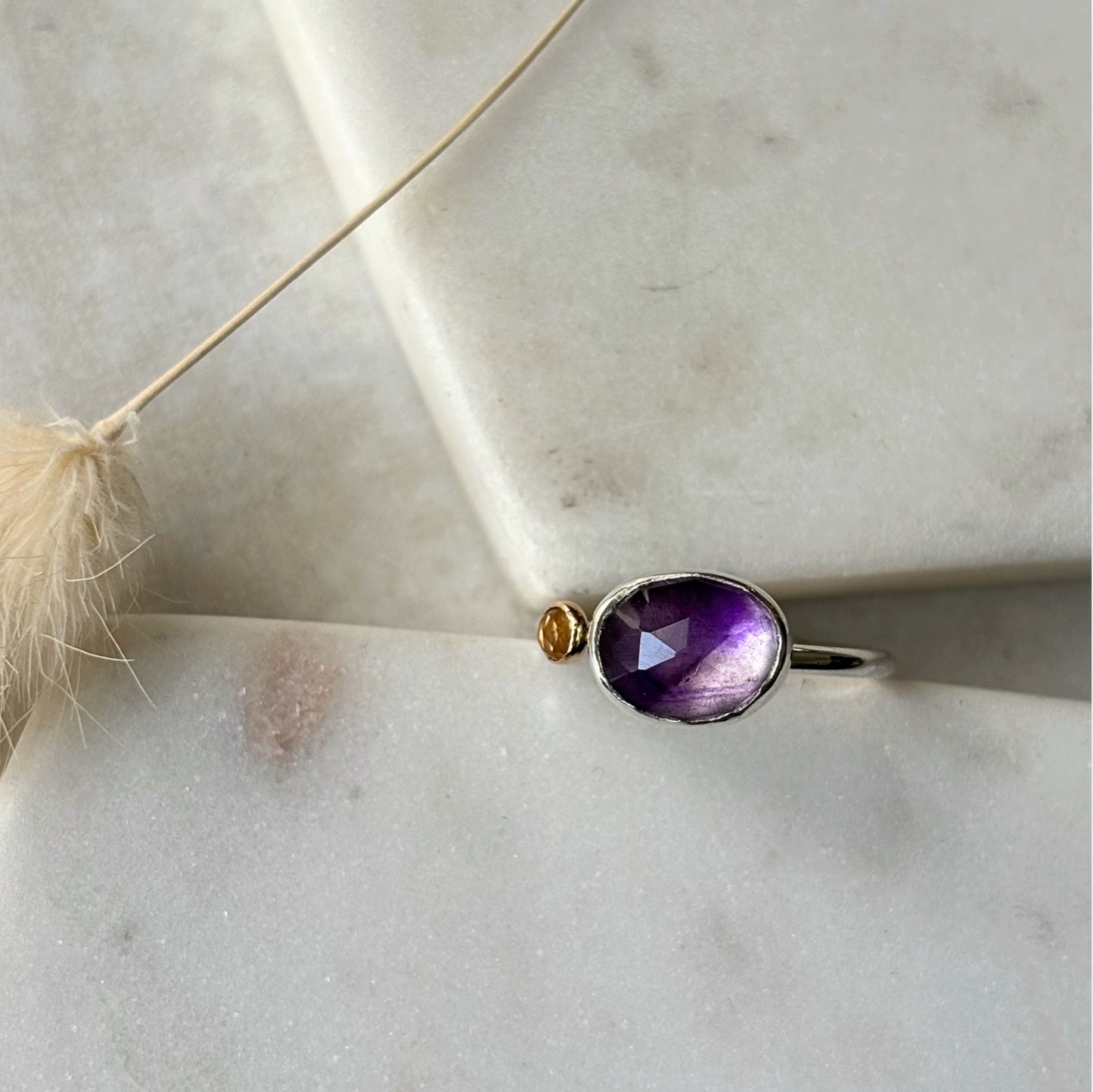 Silver ring with a purple gemstone on a light background
