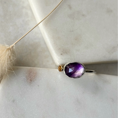 Silver ring with a purple gemstone on a light background