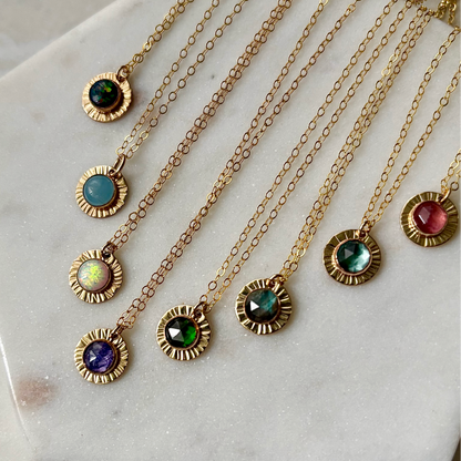 Gold necklaces with colorful gemstones on a marble surface