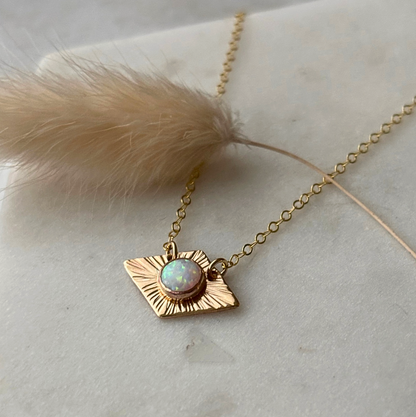 gold textured trapazoidal necklace with opal on a marble background