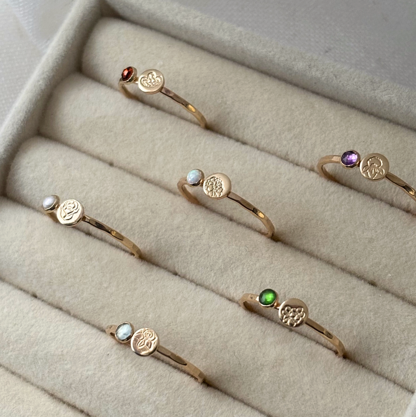 Set of gold rings with gemstones on a beige jewelry display