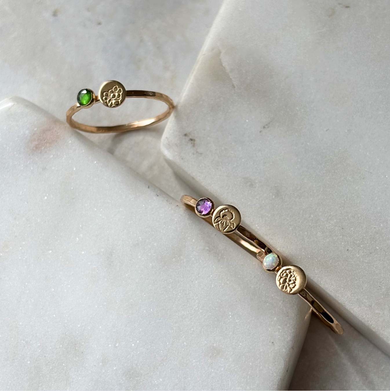 Gold ring and bracelet with gemstones on a marble surface