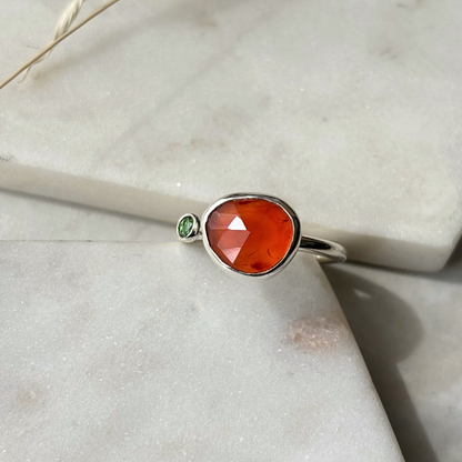 silver ring with an orange gemstone on a marble background