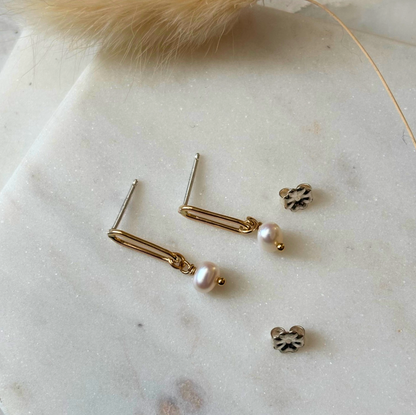 Gold and pearl earrings on a marble surface