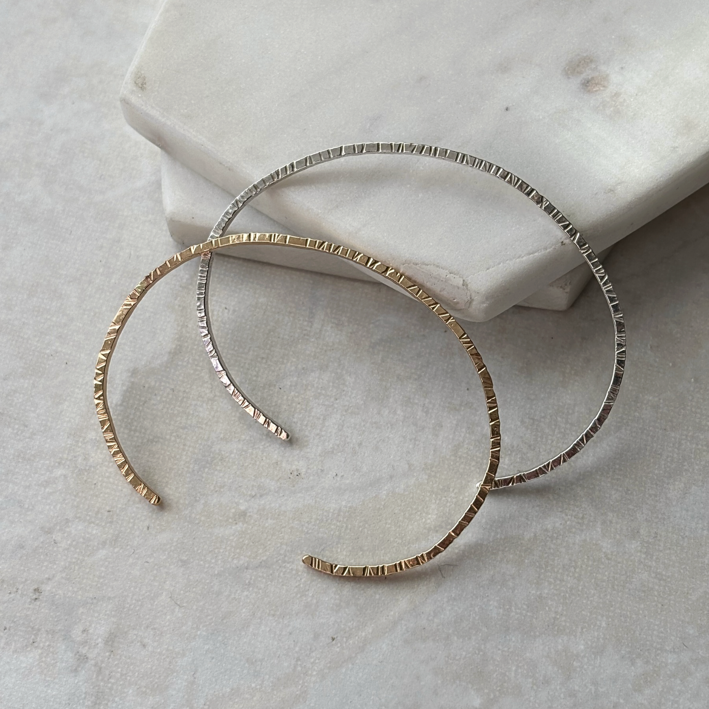 Gold cuffs on a textured stone surface