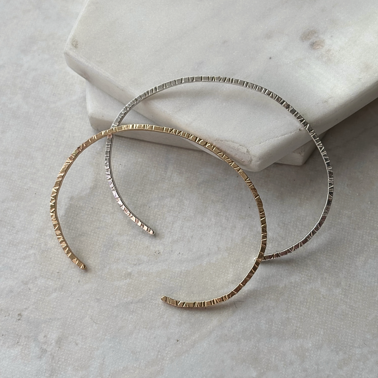 Gold cuffs on a textured stone surface