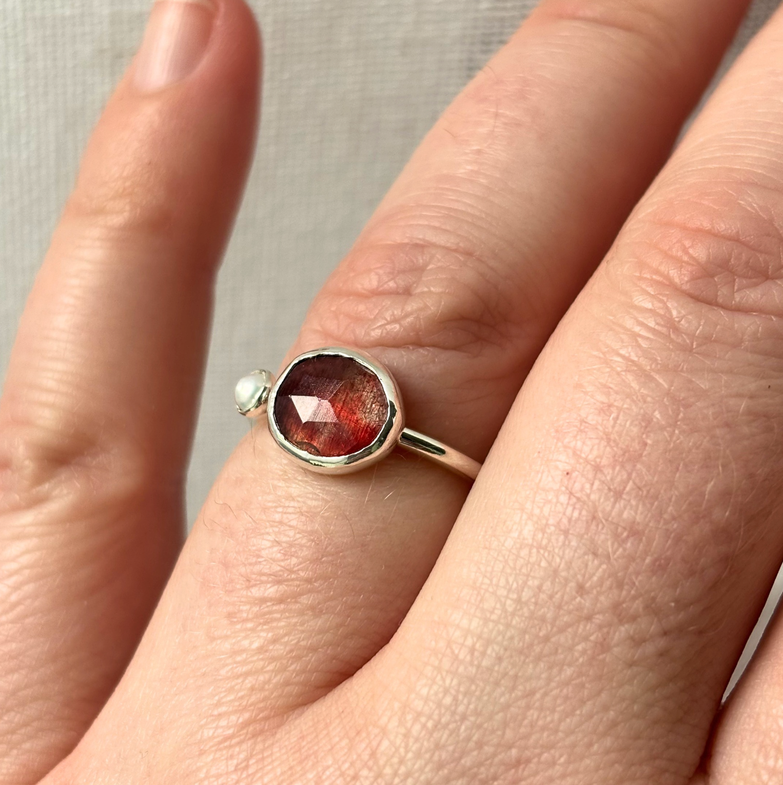 Silver ring with a red gemstone on a finger
