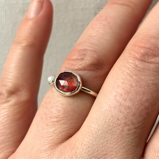 Silver ring with a red gemstone on a finger