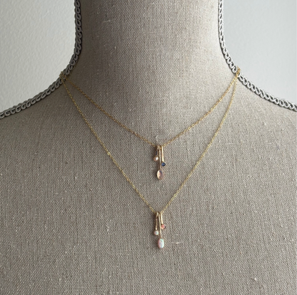 gemstone drop necklaces in gold on a textured bust