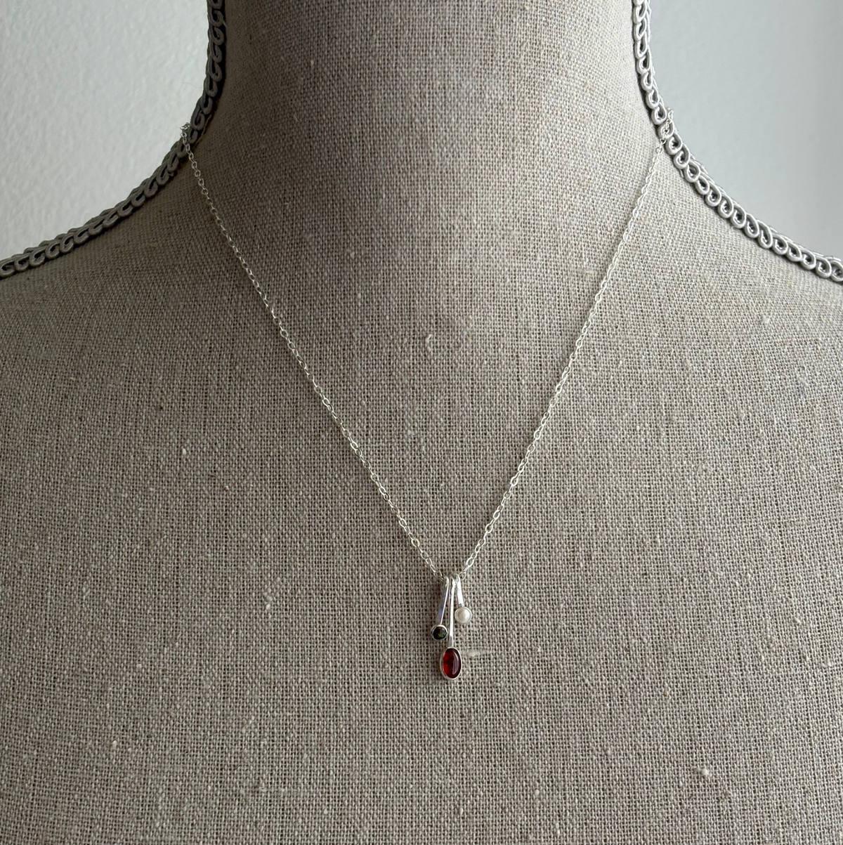 gemstone drop necklaces in silver on a textured fabric bust