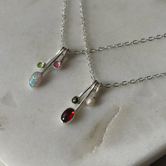 gemstone drop necklaces in silver on a marble background