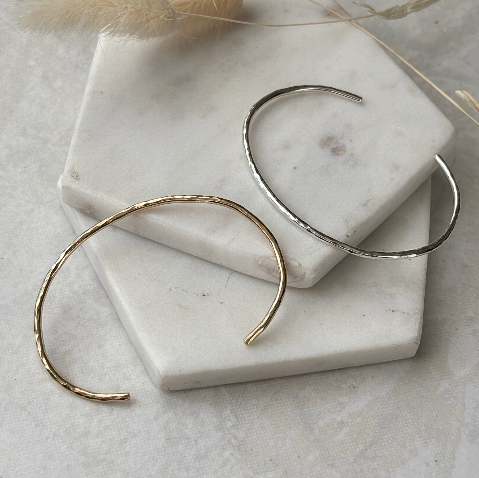 Gold and silver cuffs on a marble surface