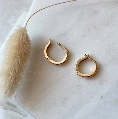 Gold hoop earrings on a light marble surface 