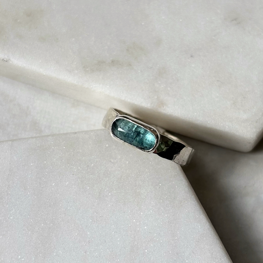 silver ring with a blue gemstone on a marble background