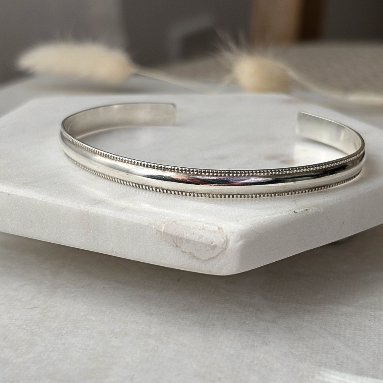 Silver bangle on a marble surface with a blurred background