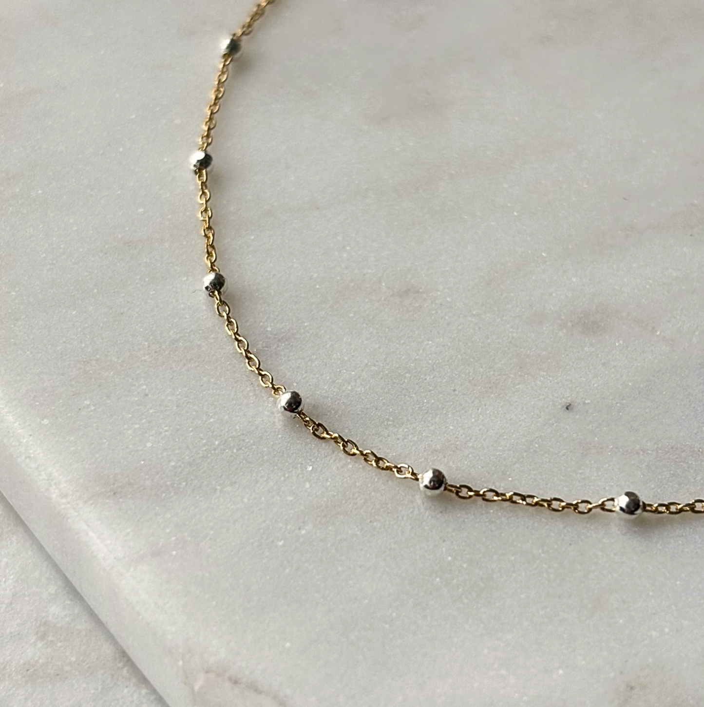 gold and silver chain bracelet on a marble background