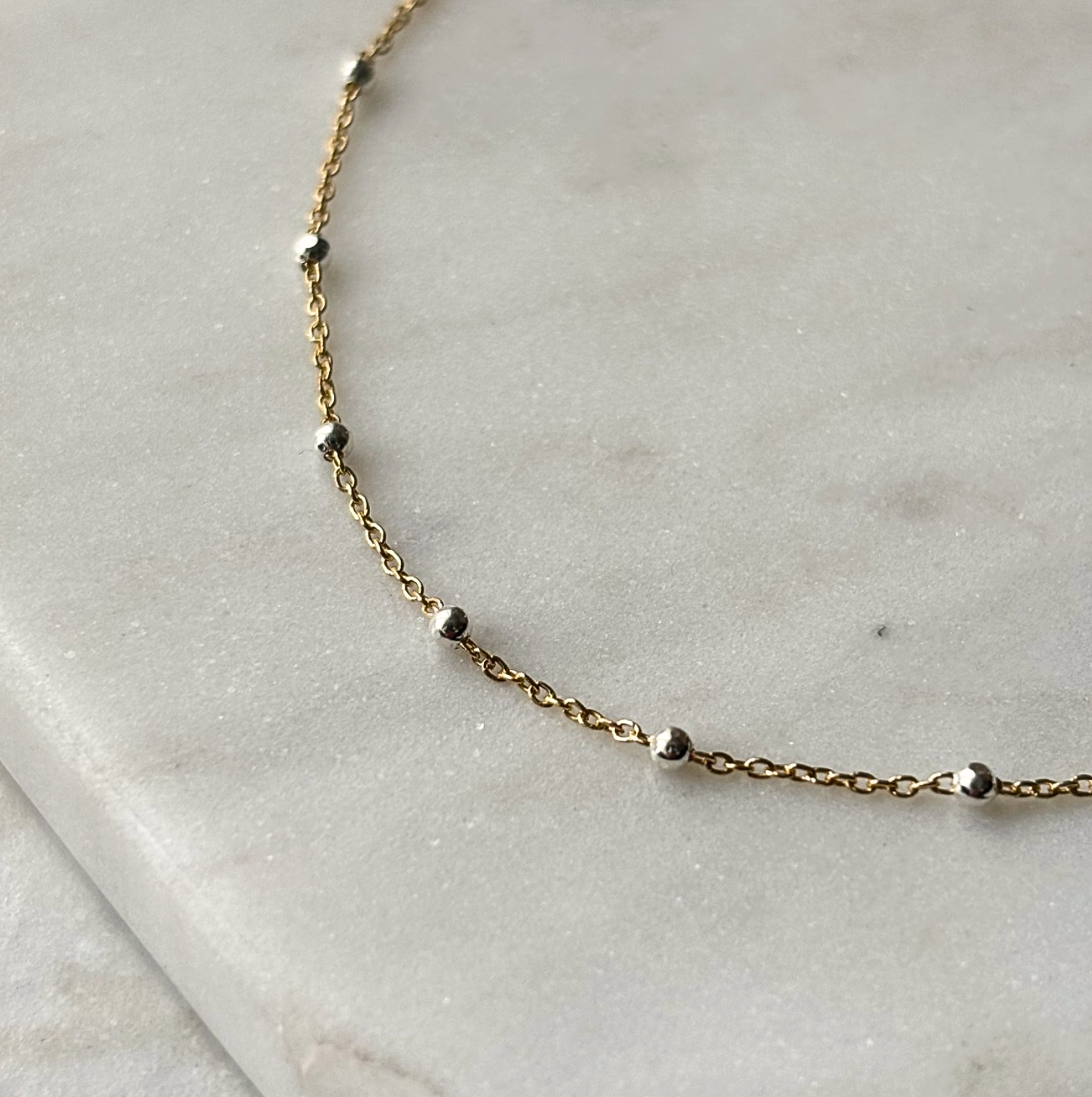 gold and silver chain bracelet on a marble background