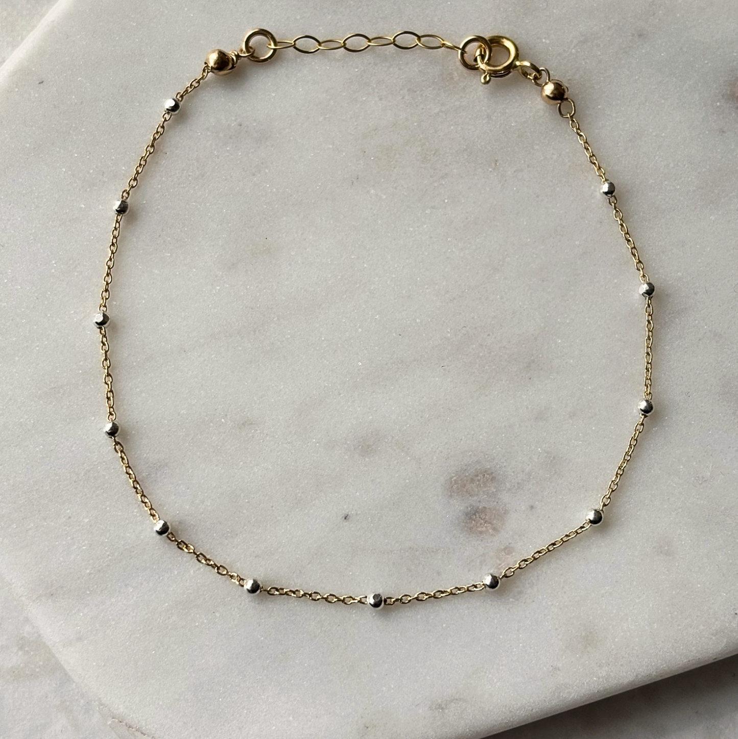gold and silver chain bracelet on a marble background