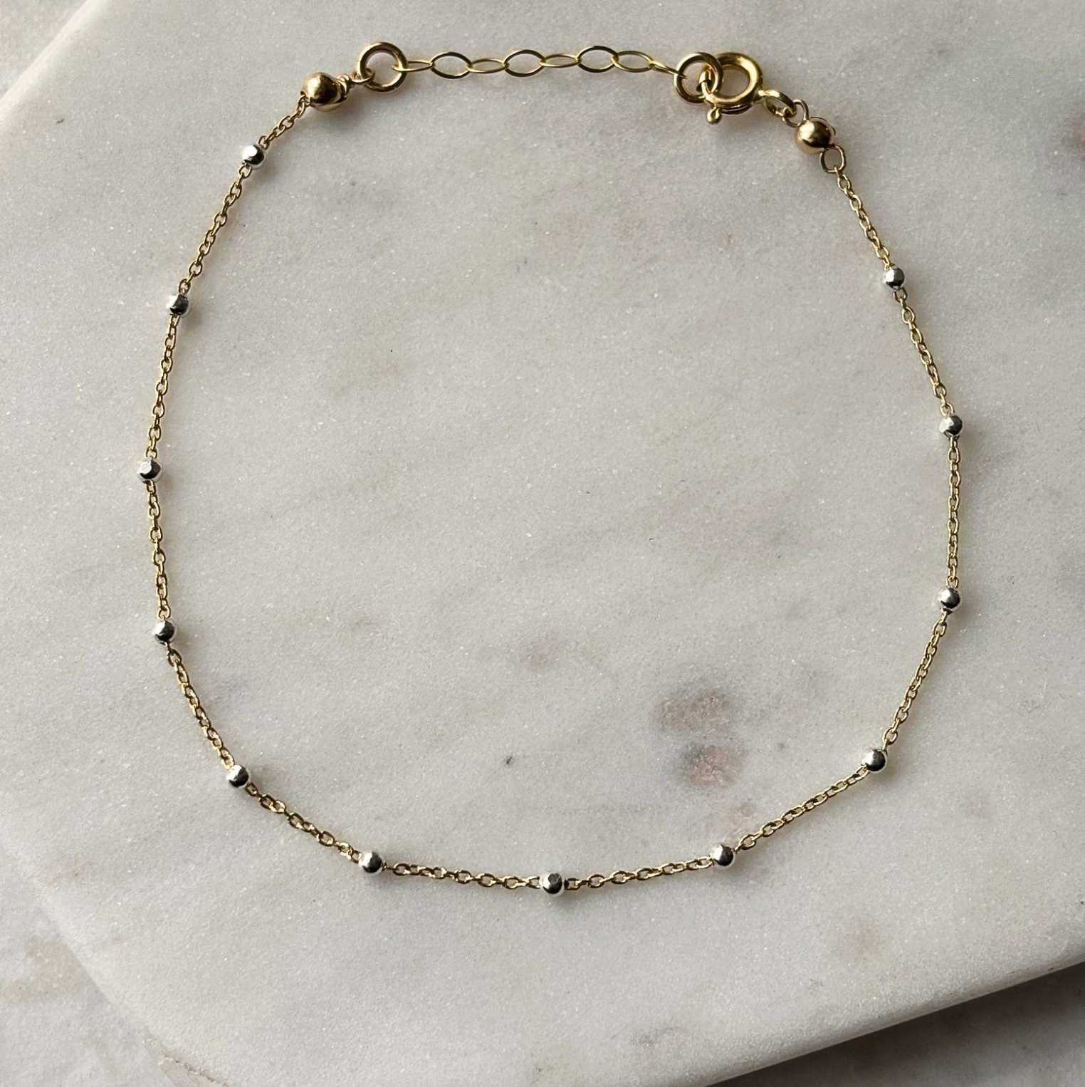 gold and silver chain bracelet on a marble background