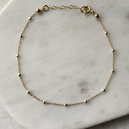 gold and silver chain bracelet on a marble background