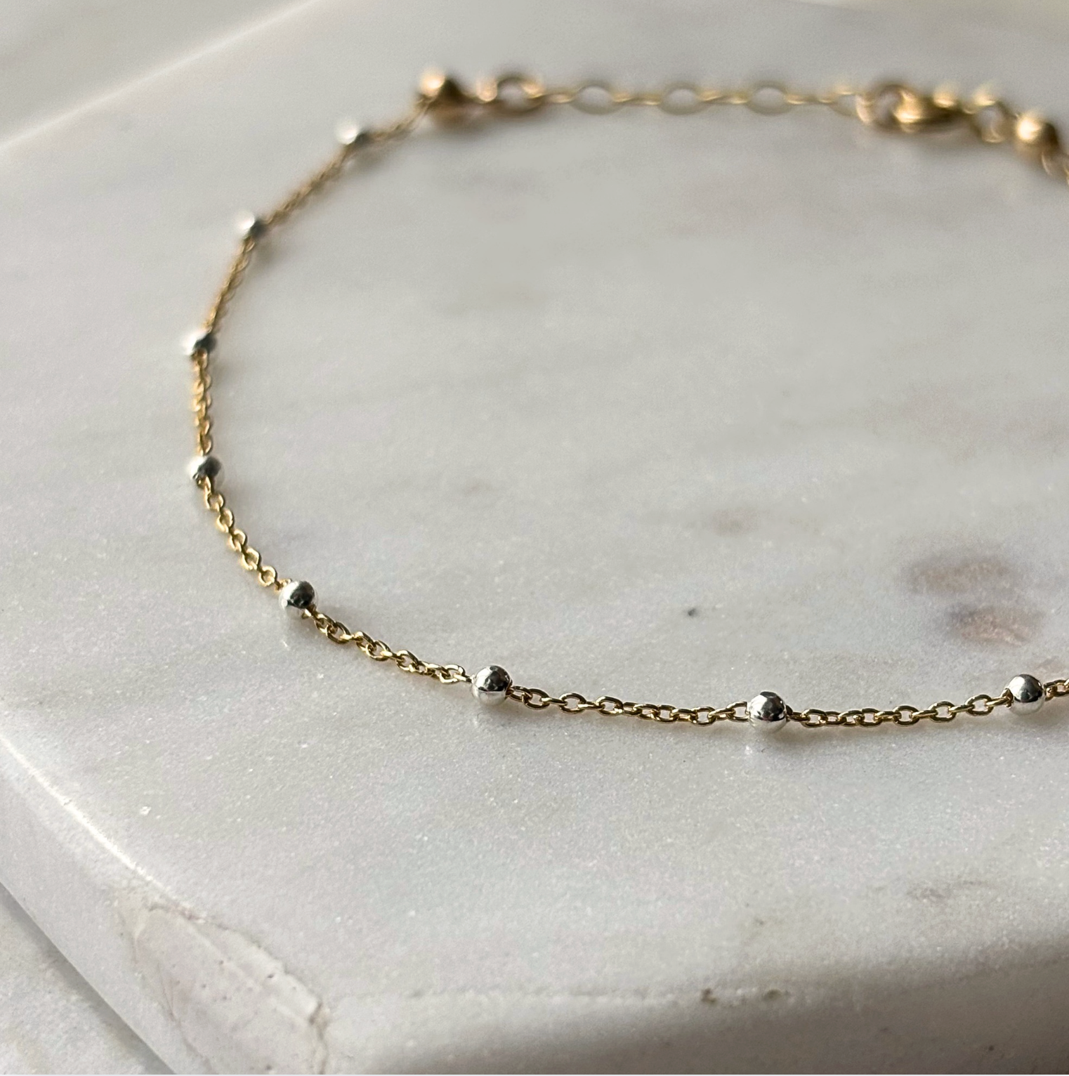 gold and silver chain bracelet on a marble background